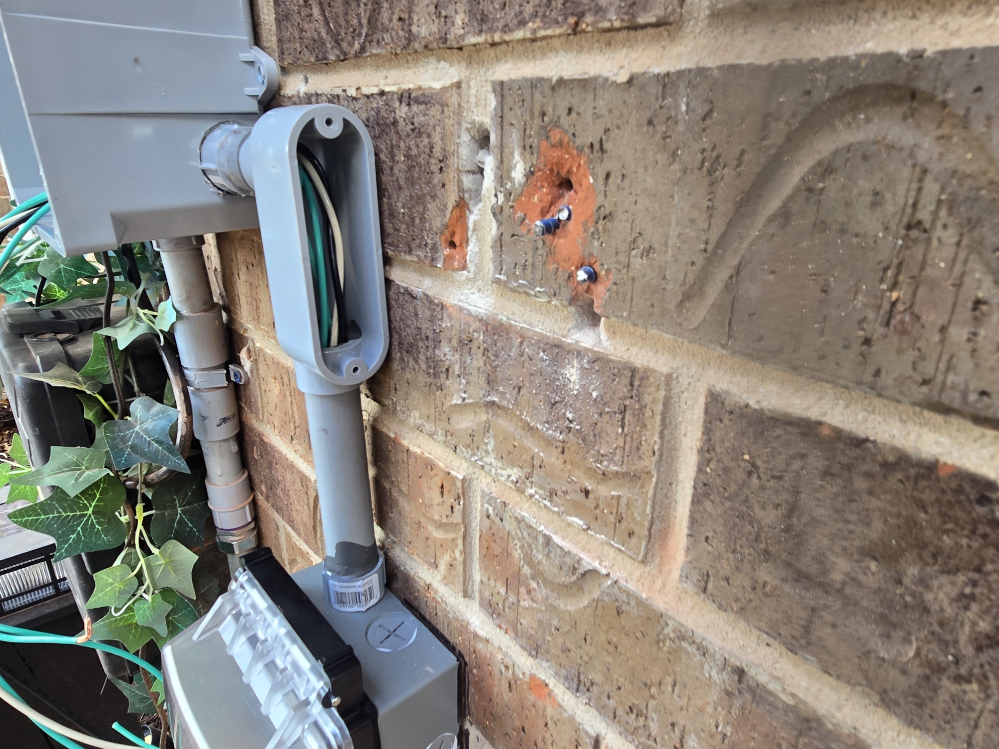 Outdoor electrical conduit and boxes during installation on a brick exterior wall